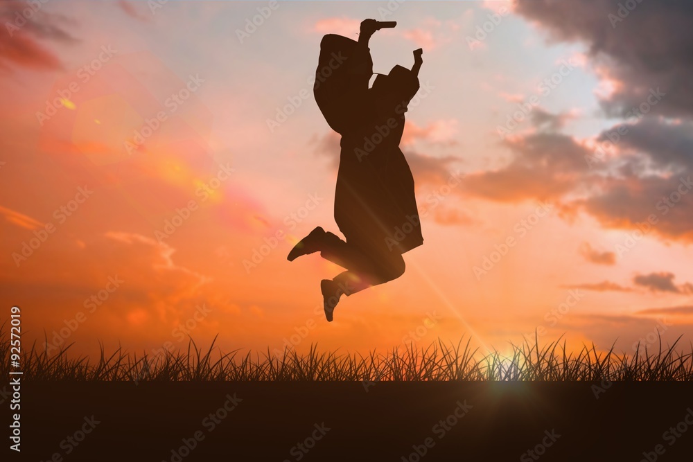 Composite image of happy male student in graduate robe jumping Composite image of happy male student in graduate robe jumping