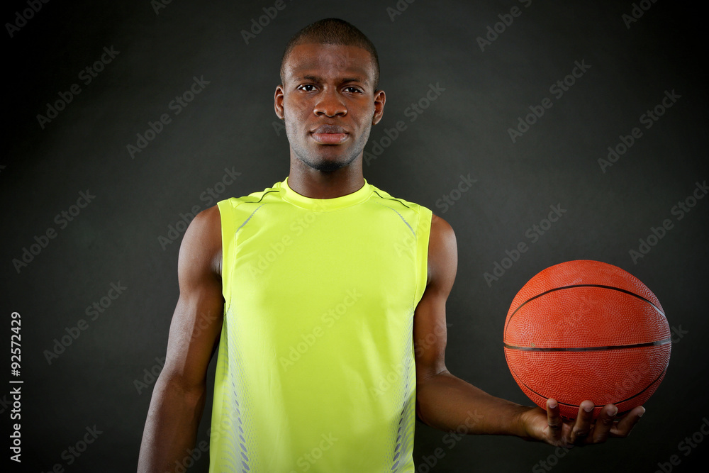 African American basketball player holding ball on dark background African American basketball player holding ball on dark background