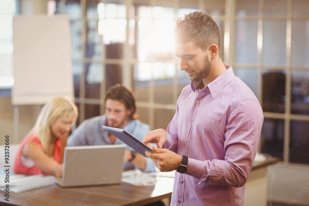 Businessman using digital tablet with colleagues on laptop Businessman using digital tablet with colleagues on laptop