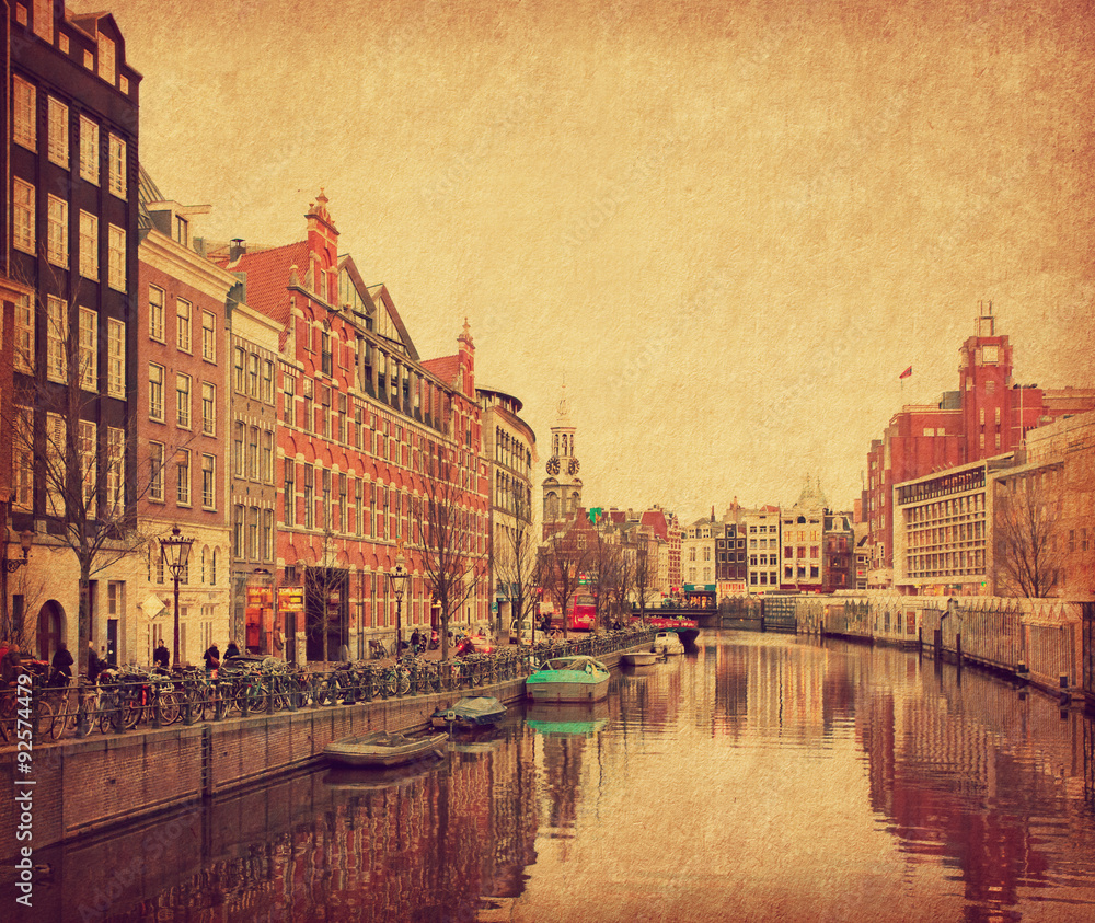The Singel is one of the numerous canals in Amsterdam, Netherlands . In the background Munttoren . Photo in retro style. Paper texture.