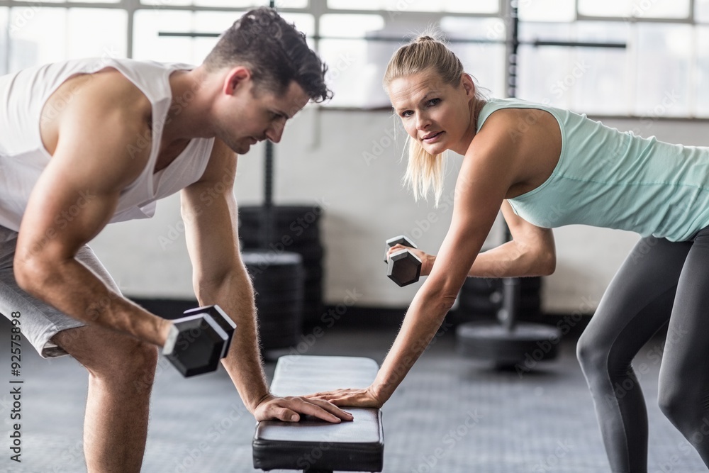 couple exercising with dumbbells in gym