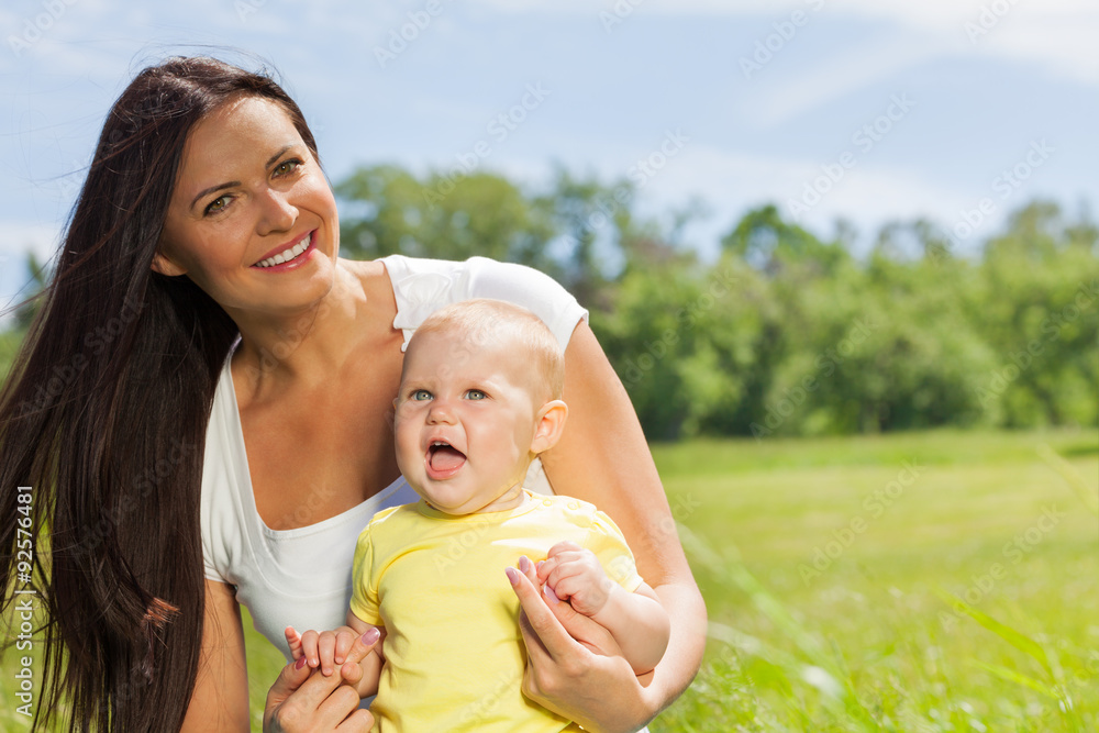 Fototapeta premium Happy mother with child in the green meadow