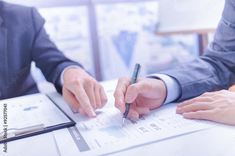 Two businessmen looking at report and having a discussion in off Two businessmen looking at report and having a discussion in off