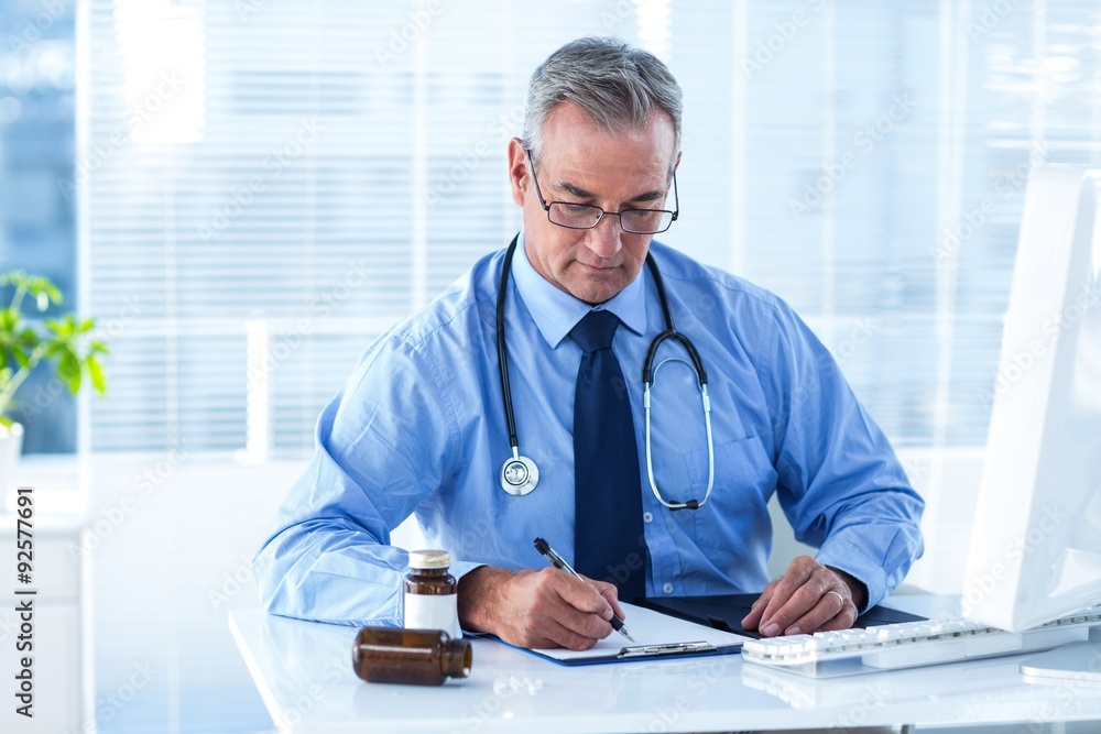 Male doctor writing prescription in hospital Male doctor writing prescription in hospital