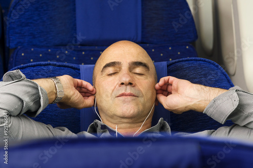 caucasian man passenger in airplane using mobile  smart device  with headphones