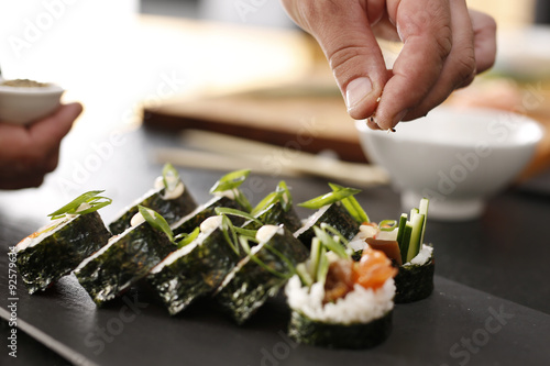 Sushi master przyrządza futomaki. Klasyczne  grube rolki futomaki podane na kamiennym talerzu
