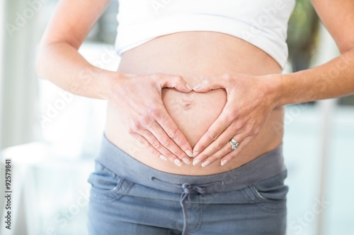 Midsection of woman hands making heart shape on belly © WavebreakmediaMicro