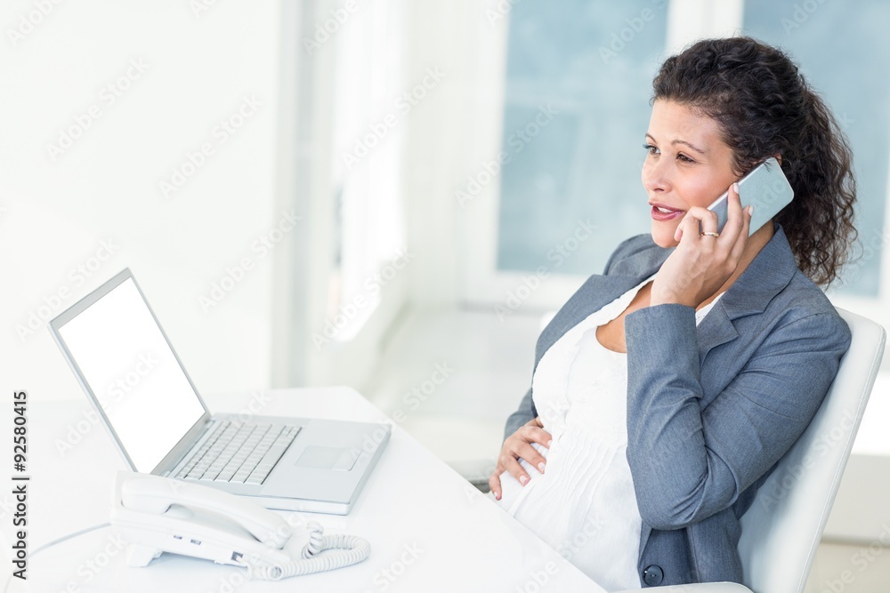 Pregnant businesswoman touching her belly and phoning Pregnant businesswoman touching her belly and phoning