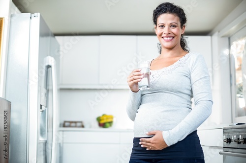 Portrait of happy pregnant woman holding a glass of water