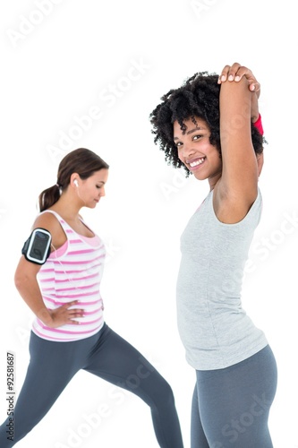 Woman exercising while female friend stretching