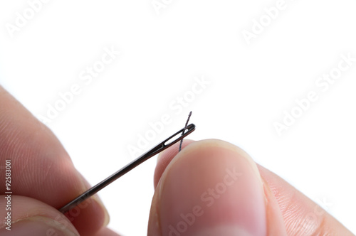 Hands passing a thread in a needle isolated on white background