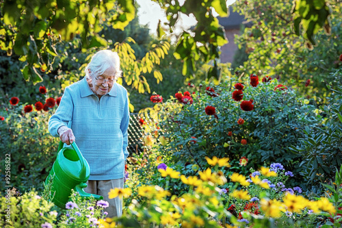 Elderly woman watering  the garden © Ingo Bartussek