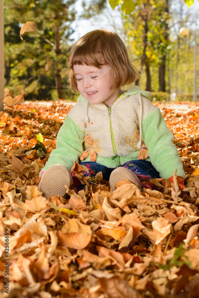 Little baby sitting and playing with fallen leaves Little baby sitting and playing with fallen leaves
