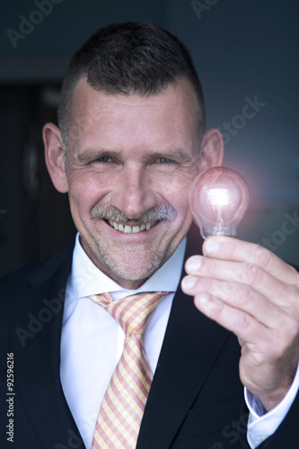 man holding a lightbulb and smiles