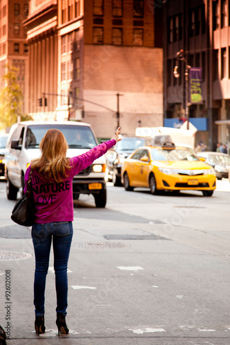Young woman waving for yellow cab