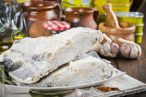 Obraz na płótnie Lomo de bacalao salado cortado, pescado seco en la mesa de la cocina con ingredientes para cocinar