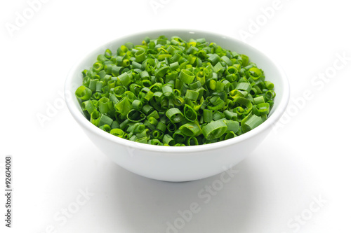 Cut tube chive leaves in white bowl, isolated background