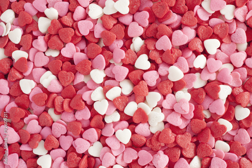Heart shaped sprinkles background. Top view of heart shaped sprinkles in white,pink and red colors for romance concept