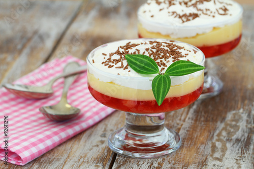 Traditional English strawberry trifle in transparent dessert glass on rustic wooden surface
 photo