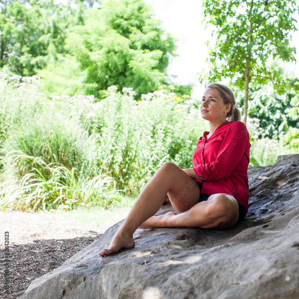 sad young woman sitting on giant stone for summer freshness sad young woman sitting on giant stone for summer freshness