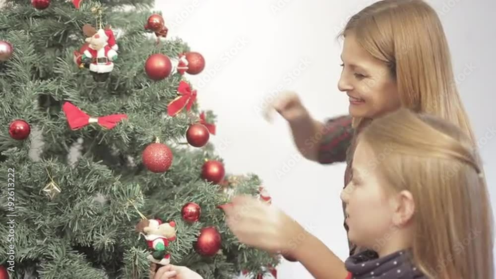 Girl with her mom decorating the christmas tree Girl with her mom decorating the christmas tree