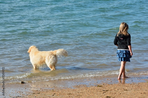 Une fillette et son beau chien se promènent sur une plage de de sable en Bretagne