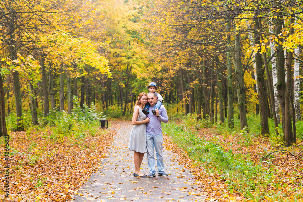 Fototapeta premium Young family for a walk in the autumn park with baby