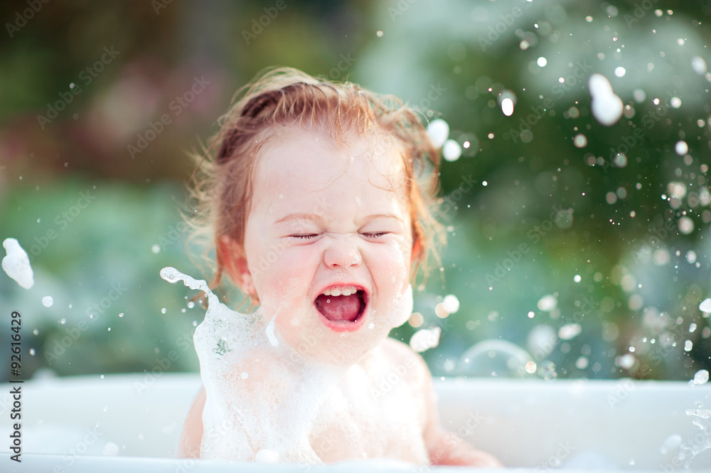 Laughing baby girl having fun washing in bath outdoors. Cheerful. Happiness. Childhood. Laughing baby girl having fun washing in bath outdoors. Cheerful. Happiness. Childhood.