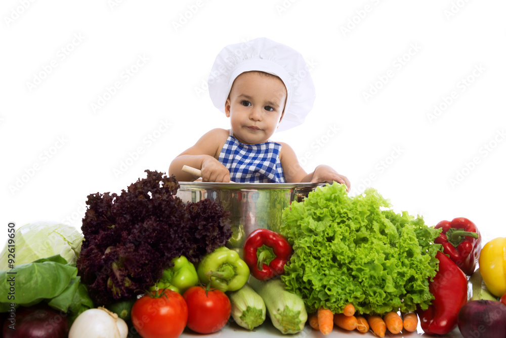Little boy in chef's hat sitting in pot with vegetables Little boy in chef's hat sitting in pot with vegetables