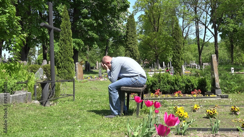 Stressed man sit shrink on bench near mother lover grave in cemetery. Flowers move in wind. Static shot. 4K
Stressed man sit shrink on bench near mother lover grave in cemetery. Flowers move in wind. Static shot. 4K