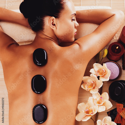 Adult woman relaxing in spa salon with hot stones on body