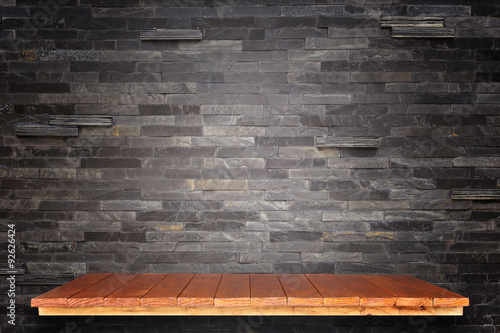 Empty wooden shelves and stone wall background