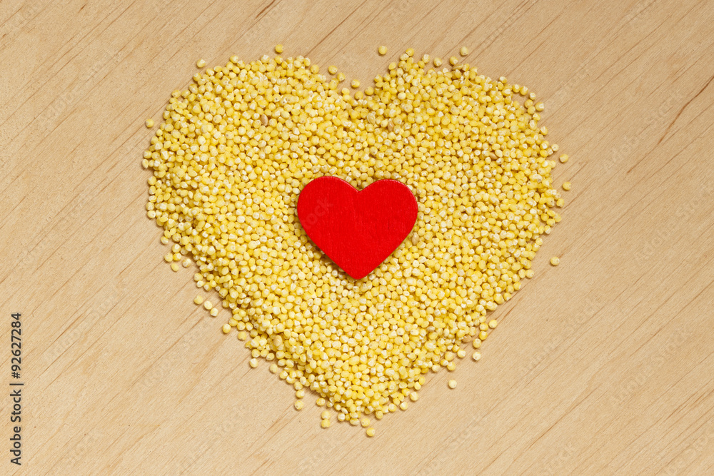Millet groats heart shaped on wooden surface. Millet groats heart shaped on wooden surface.