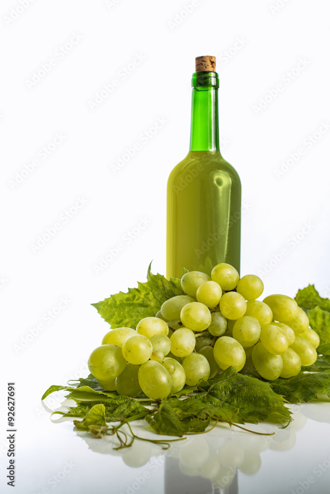 Bottle of fresh white wine with green grapes on white background