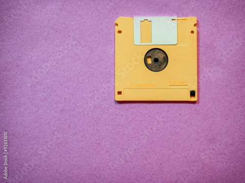 Vintage yellow floppy disk on Magenta background