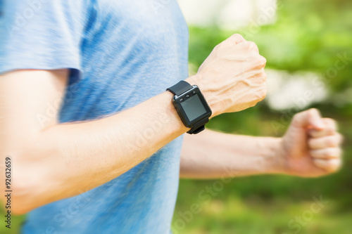 Male runner jogging outside with his smart watch