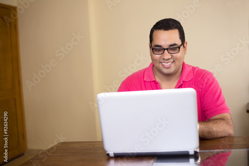 happy young latino man working on a computer