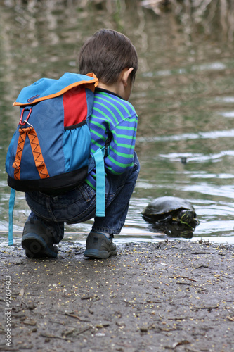 Boy looks at turtle in swamp