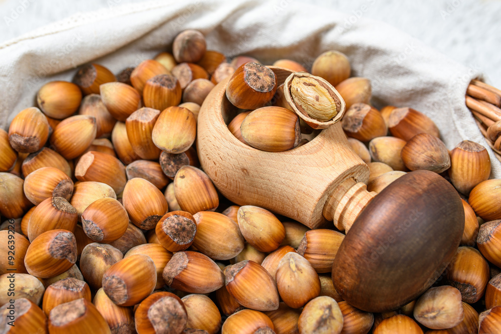 Many hazel nuts and wood cracker in wicker basket Many hazel nuts and wood cracker in wicker basket