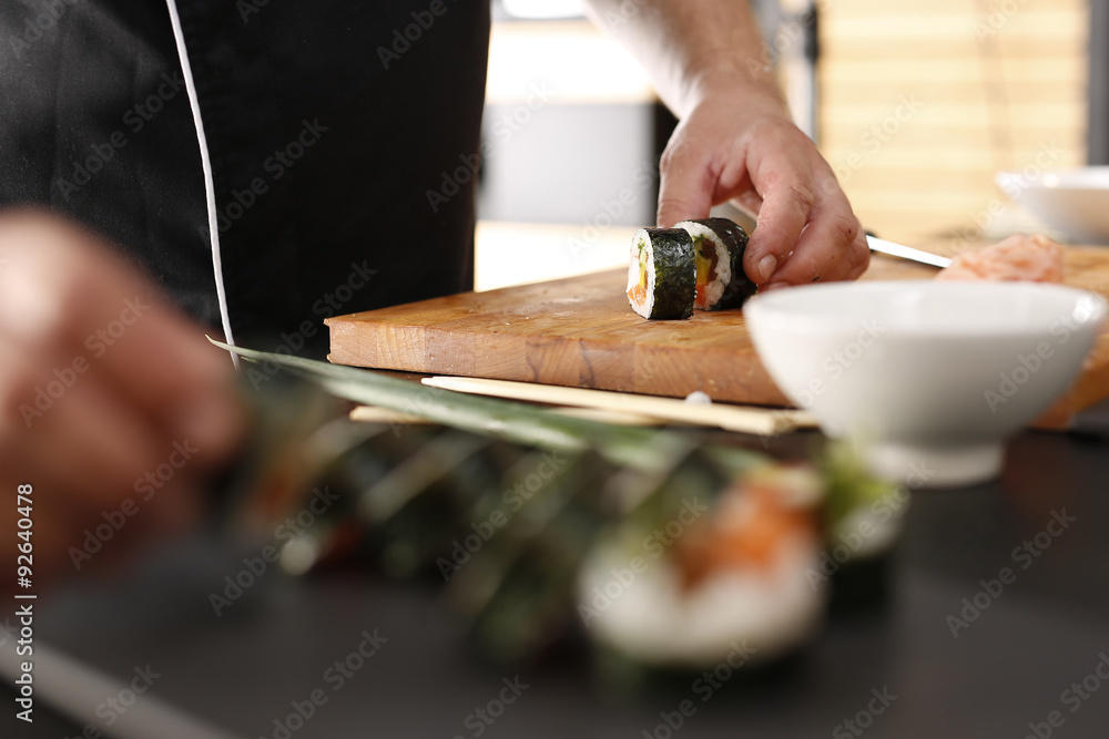 Restauracja japońska, sushi. Sushi z łososiem, krewetką i ogórkiem przygotowywane przez kucharza Restauracja japońska, sushi. Sushi z łososiem, krewetką i ogórkiem przygotowywane przez kucharza