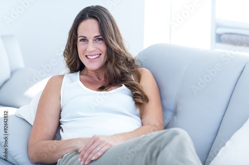 Free Download Smiling pregnant woman leaning on sofa - GFXLoad