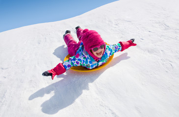 little girl riding on snow slides in winter time