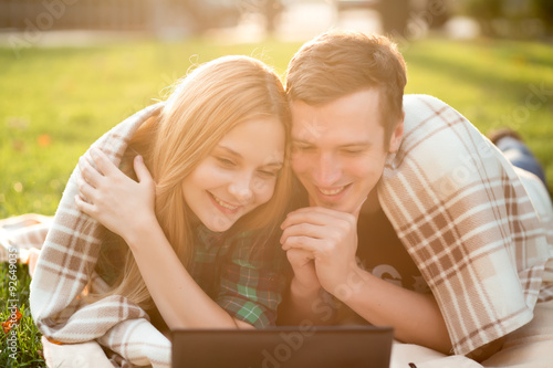 Young couple lying in the grass with a netbook