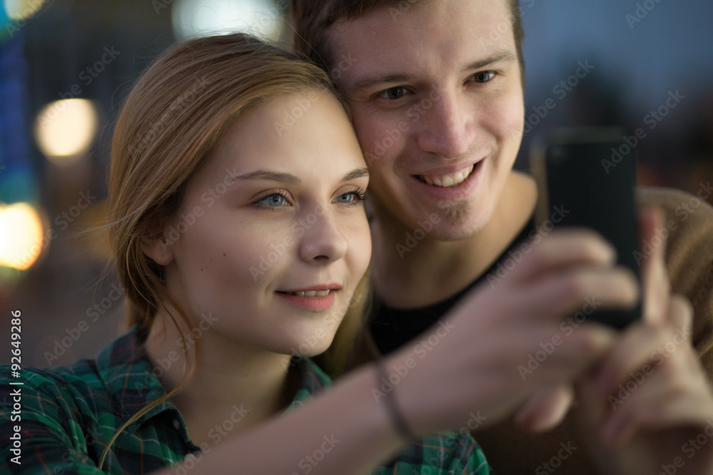 Young couple making self in evening. Amusement park background. Young couple making self in evening. Amusement park background.