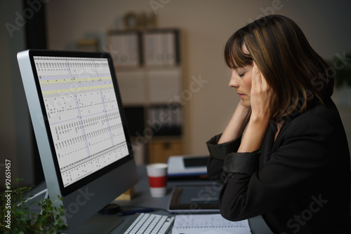 Foto frau im büro arbeitet bis spät am abend und hat kopfschmerzen