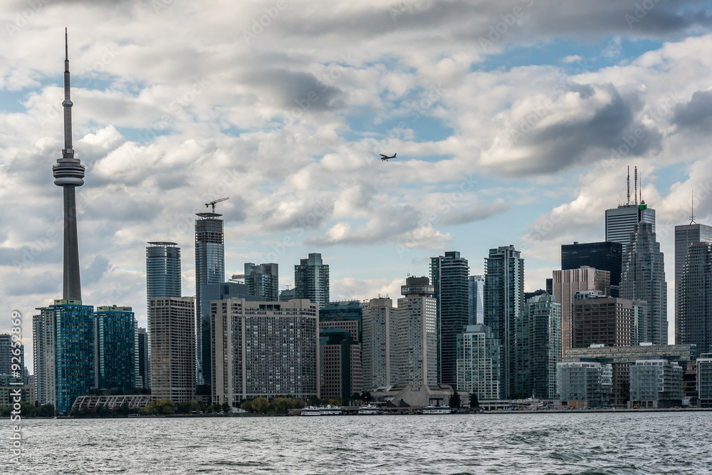 A small airplane flies above the skyscrapers of Old Toronto