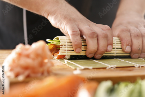 Dłonie kucharza przygotowującego sushi