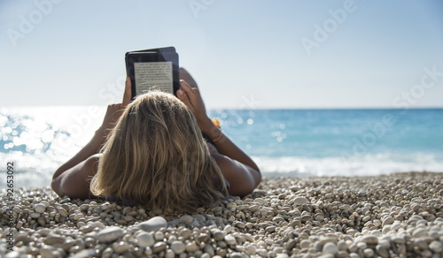 Young woman reading a ebook at beach, relax! photo