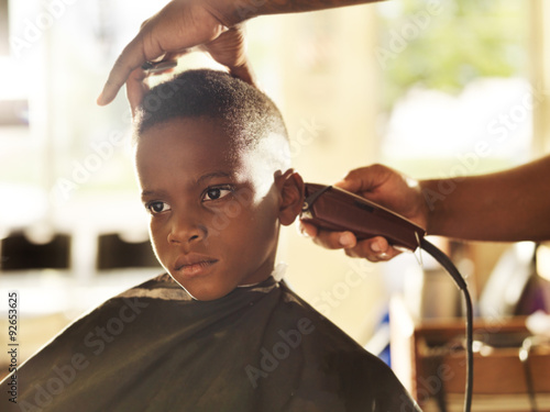 little boy getting his head shaved by barber
