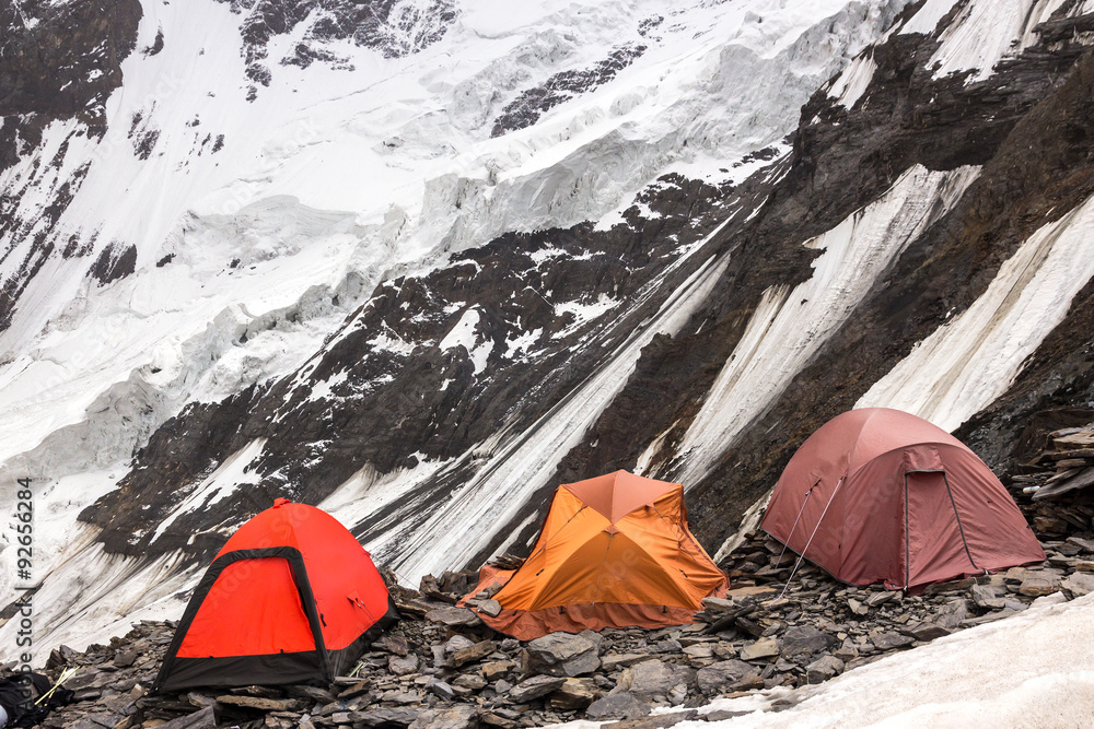 Three Alpine Tents Settled on Edge of Abyss Mountain Climbers Camp on Rock Moraine of Glacier High Altitude Severe Landscape